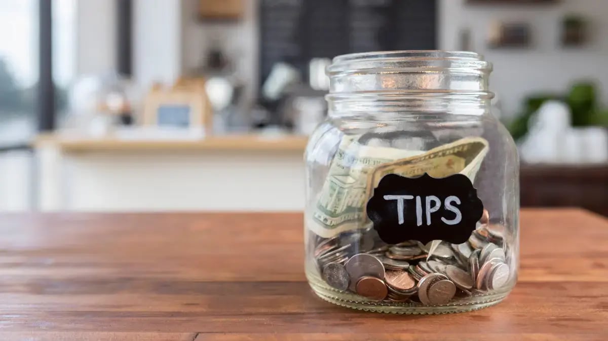 tip jar filled with money and coins on a table