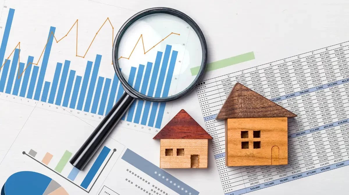 houses on top of financial reports with a magnifying glass